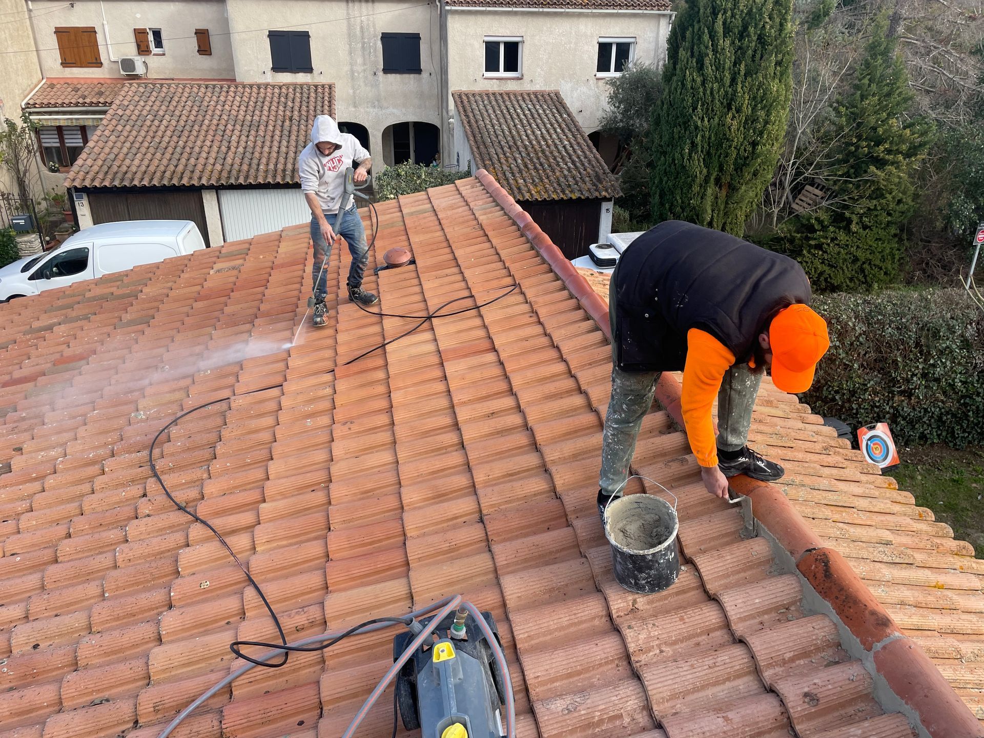 Deux ouvriers sur un toit qui nettoient et réparent