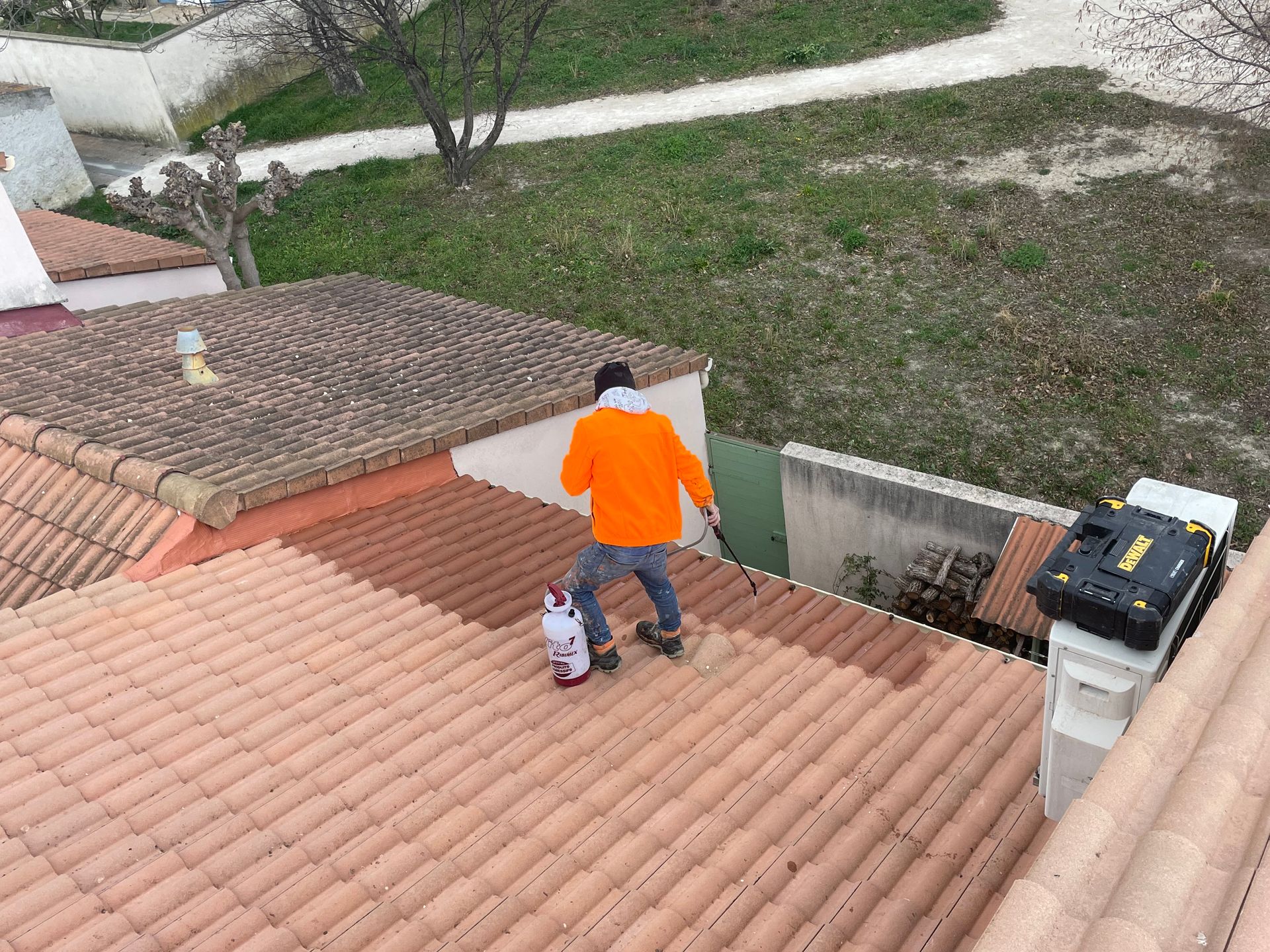Nettoyage d'un toit en tuiles par un homme debout avec une veste orange