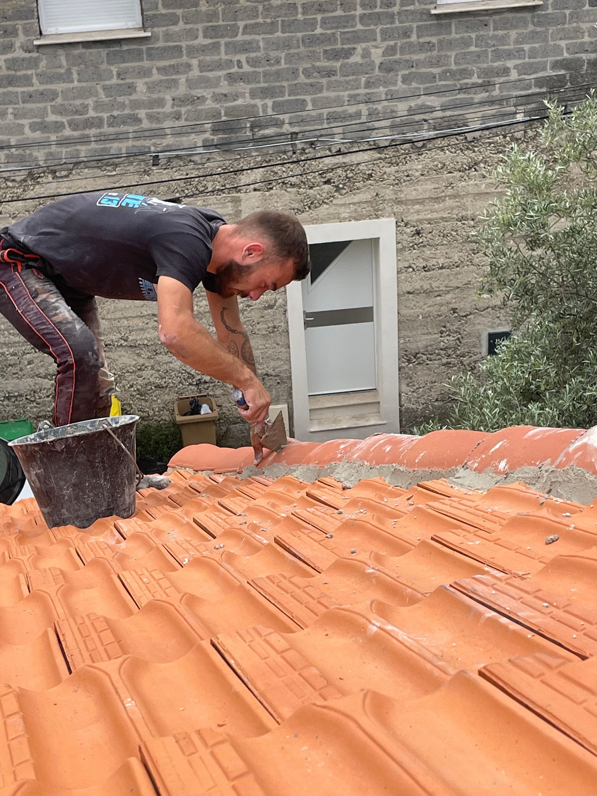 Ouvrier rénovant la bordure du toit en cimentant les tuiles