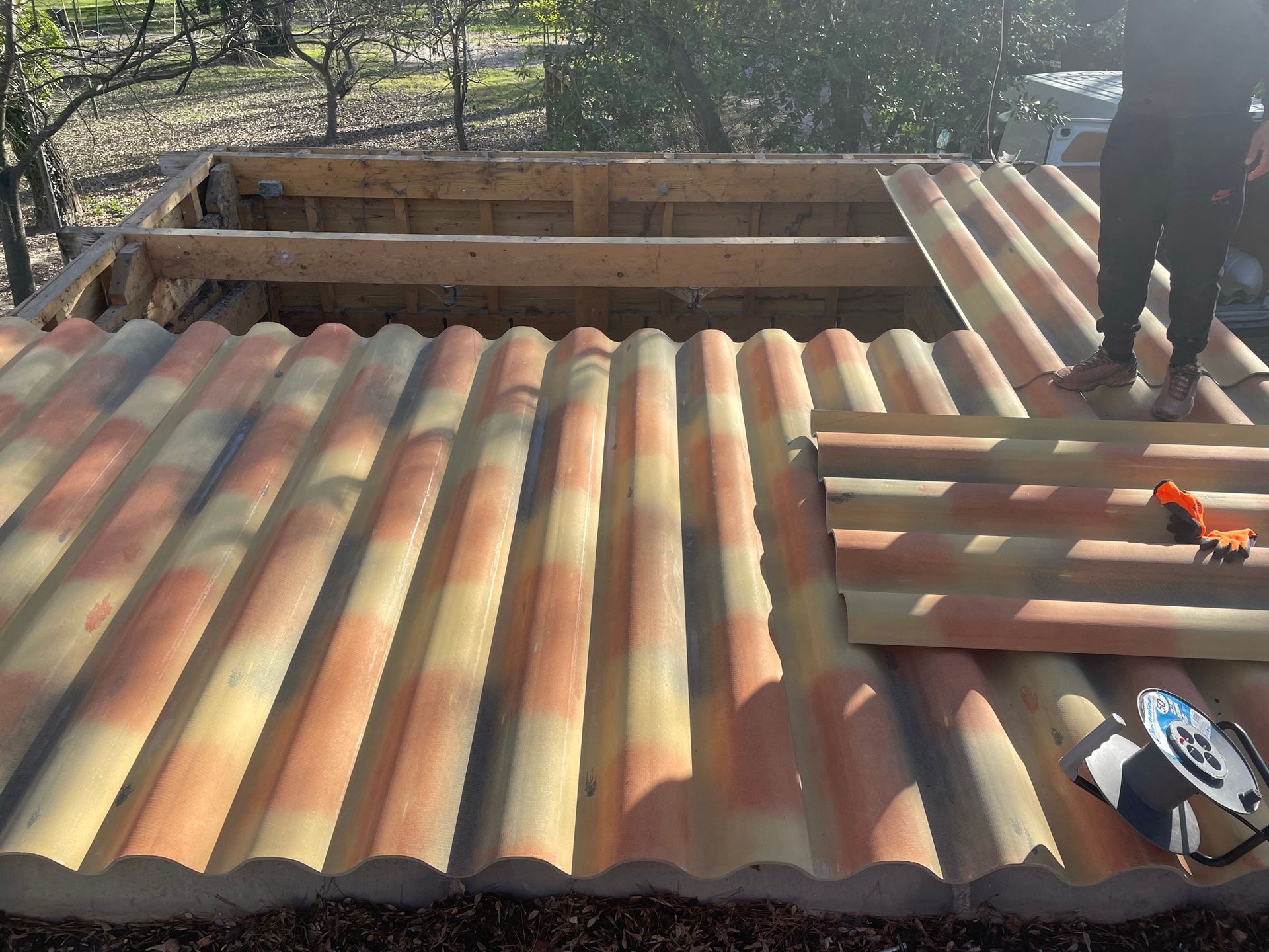 Plaques de tuilage en installation sur le toit d'un appenti