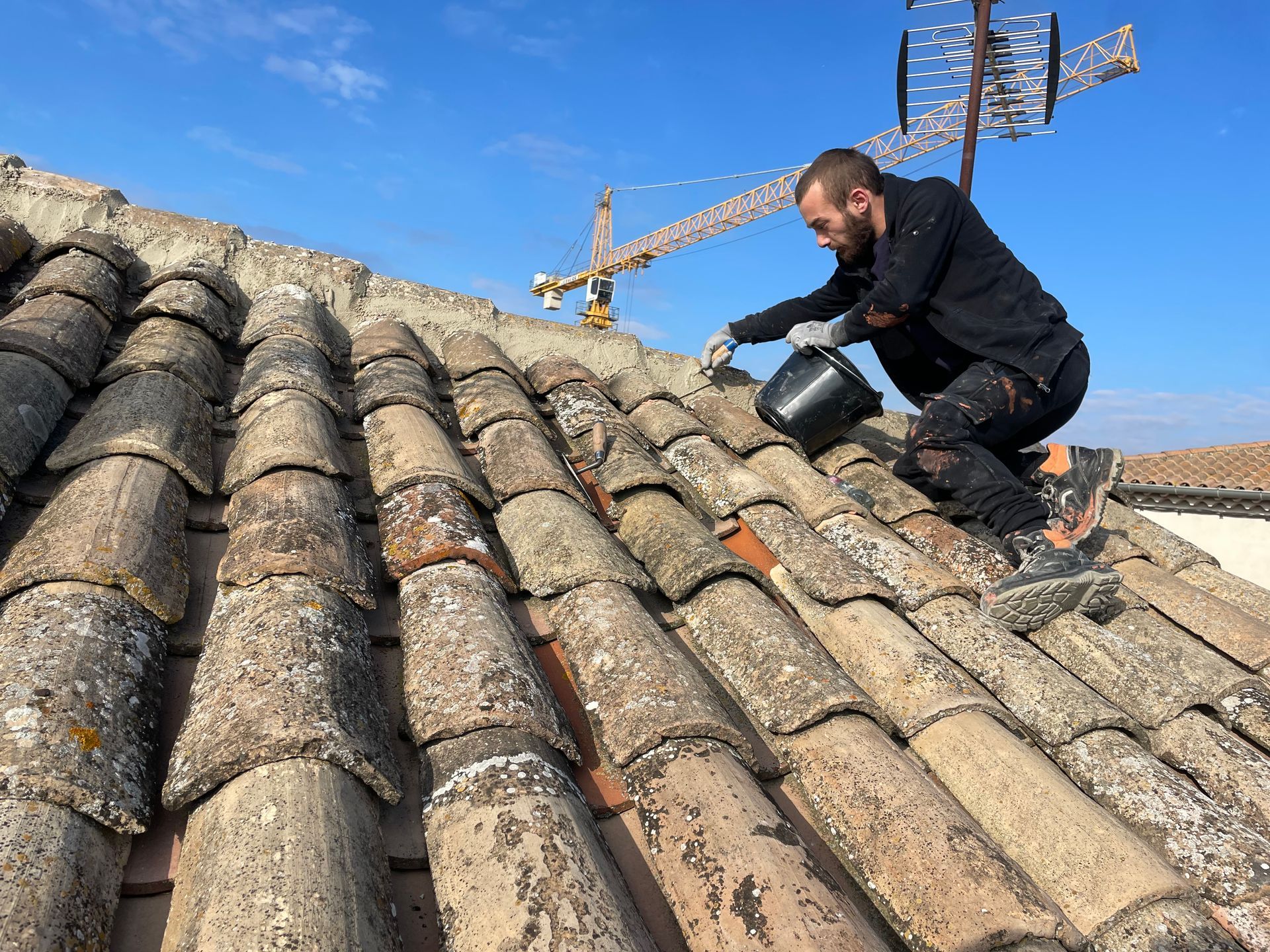 Artisan appliquant du ciment sur un faîtage