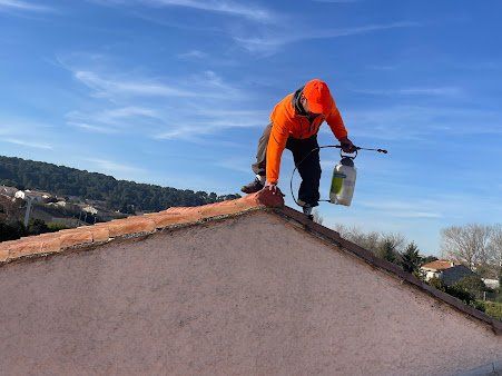 Homme en veste et casquette orange en équilibre au borde d'un toit