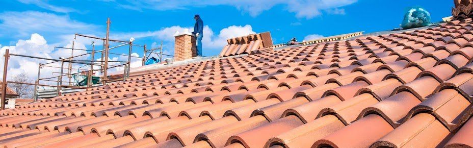vue d'un toit avec des tuiles entreposées au sommet et un homme tenant la cheminiée