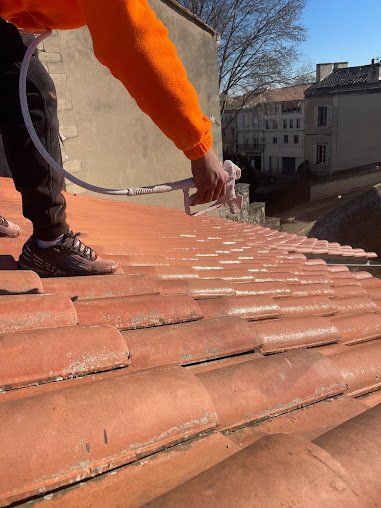 Ouvrier appliquant de la peinture hydrofuge sur les tuiles d'un toit