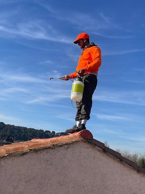Homme en haut orange debout sur le faîtage d'une maison