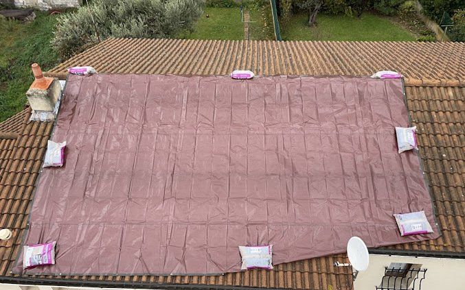 grande bâche rouge recouvrant la moitié d'un toit