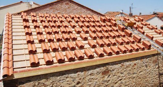 tuiles rangées sur une charpente en attente d'être posées