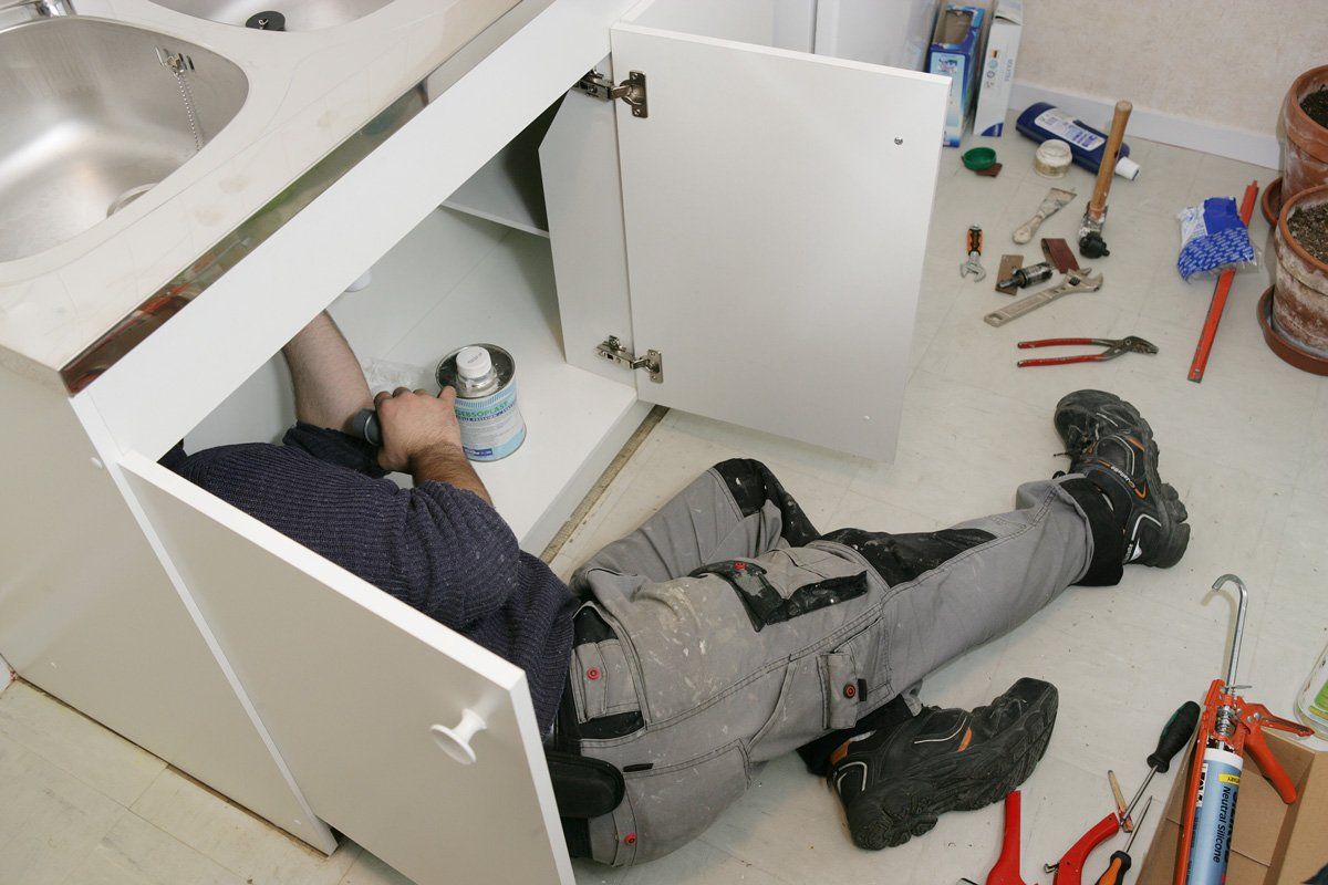 Plombier réparant des éléments sous l'évier