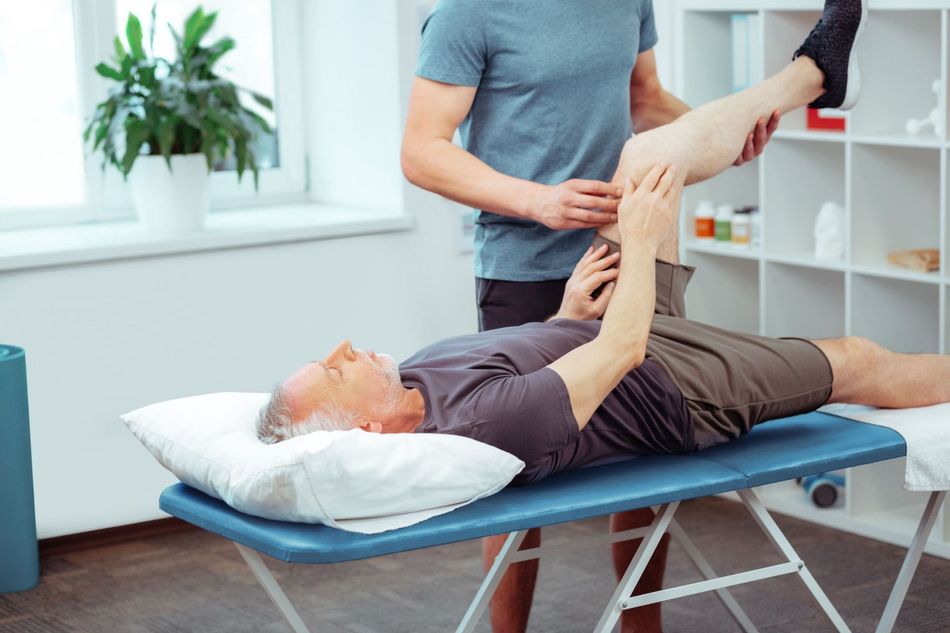 Un hombre está acostado en una mesa mientras un médico le examina la pierna.