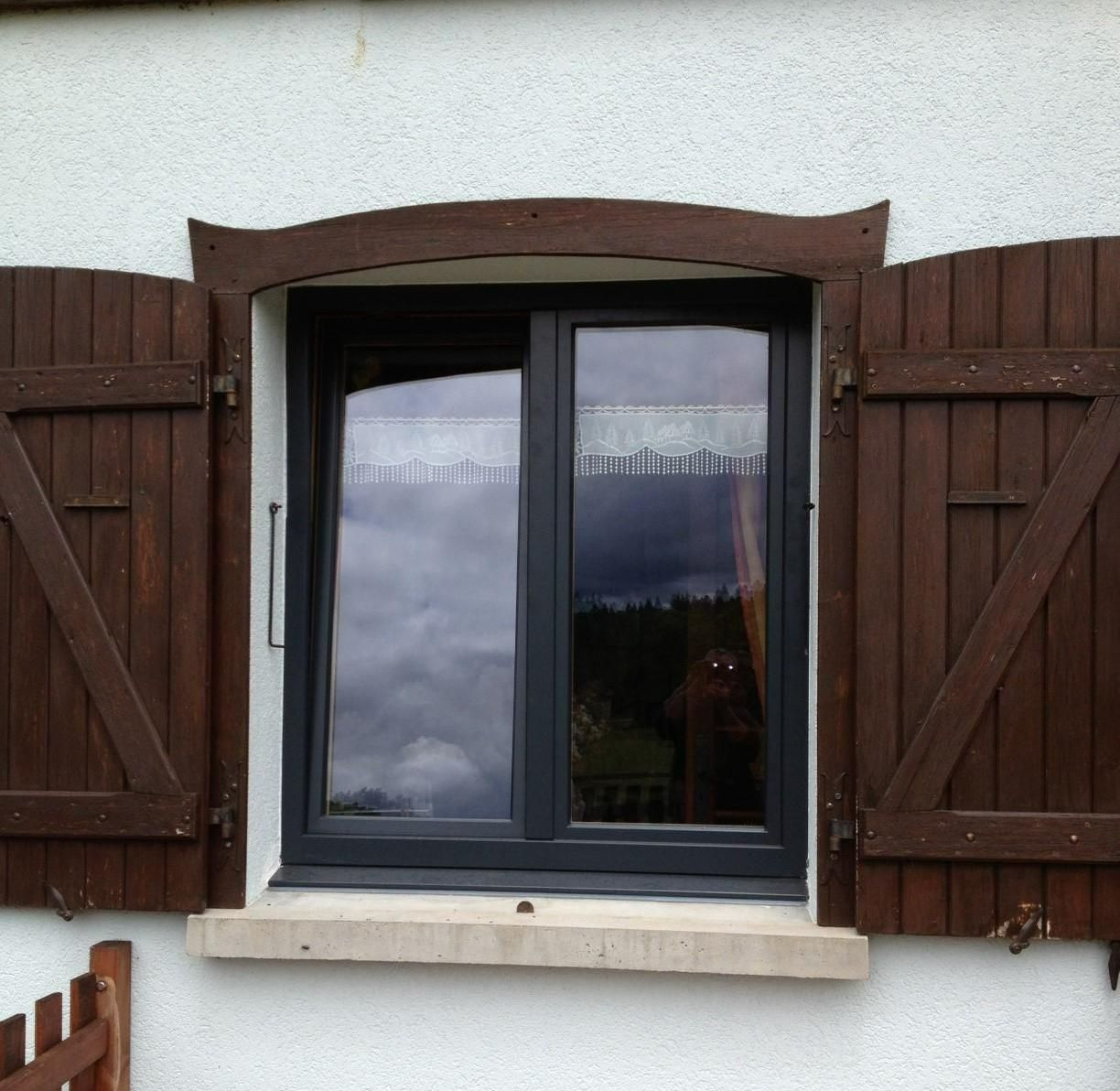Fenêtre en aluminium et volets en bois.