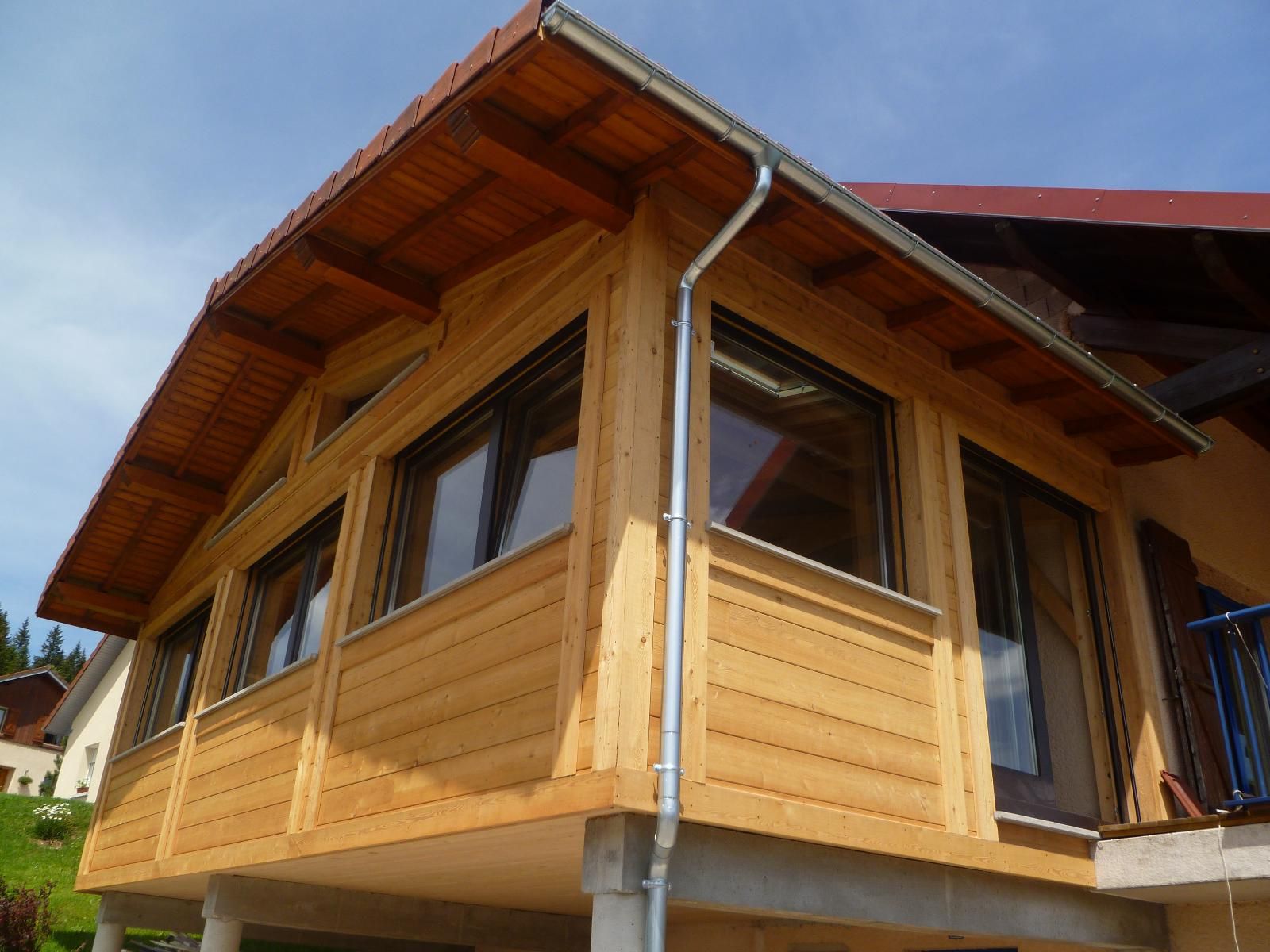 Véranda en bois avec des menuiseries en aluminium.