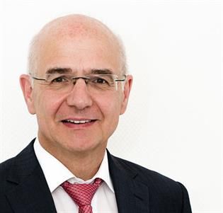 Ein kahlköpfiger Mann mit Brille, Anzug und Krawatte