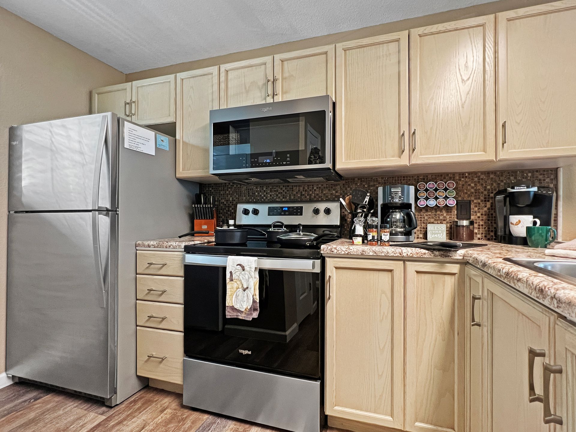 A kitchen with stainless steel appliances , a refrigerator , stove , microwave and sink.