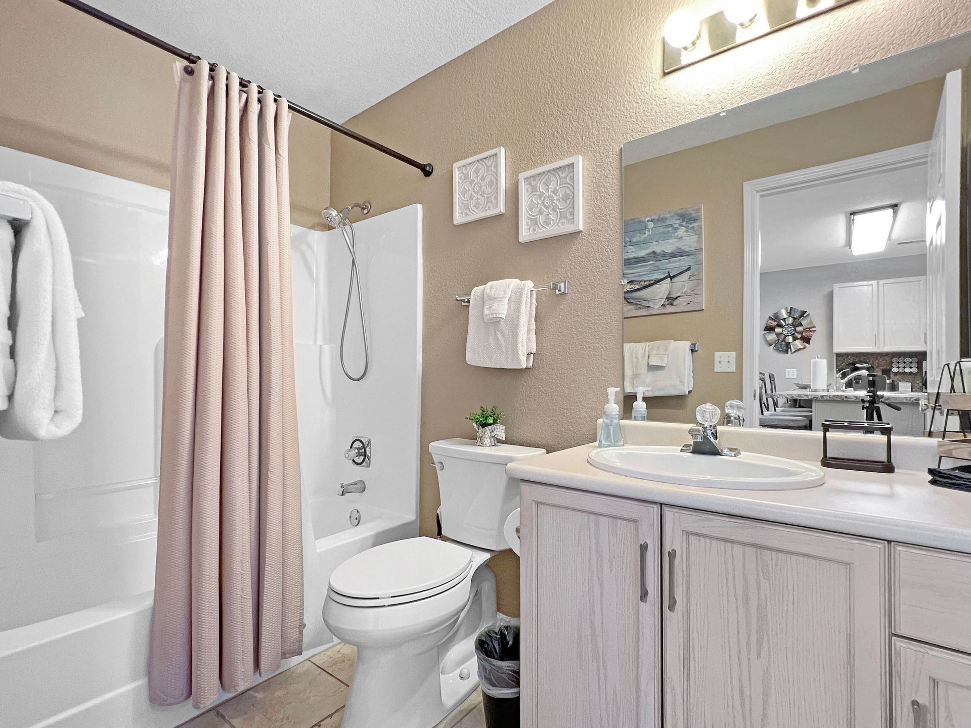 A bathroom with a toilet , sink , shower and mirror.