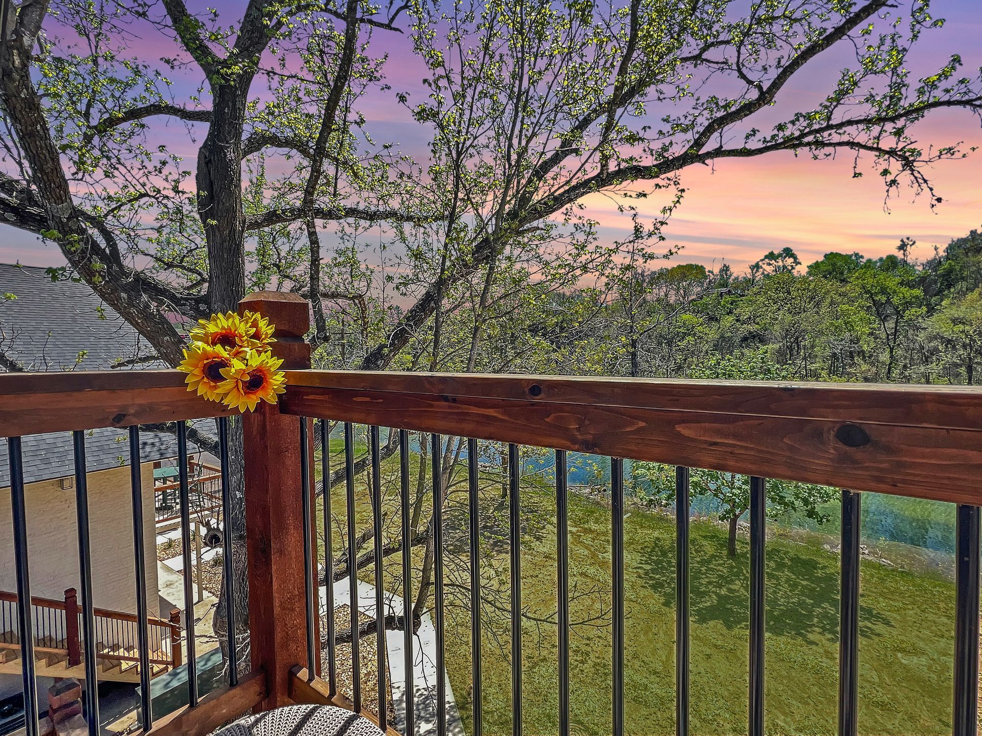 A wooden deck with a sunflower on the railing at sunset.