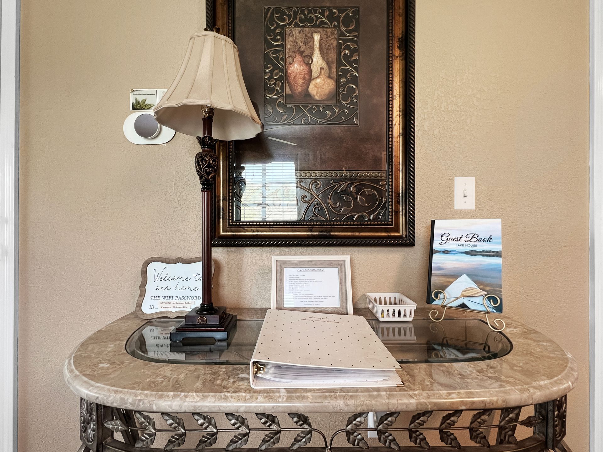 A table with a lamp and a picture on the wall.