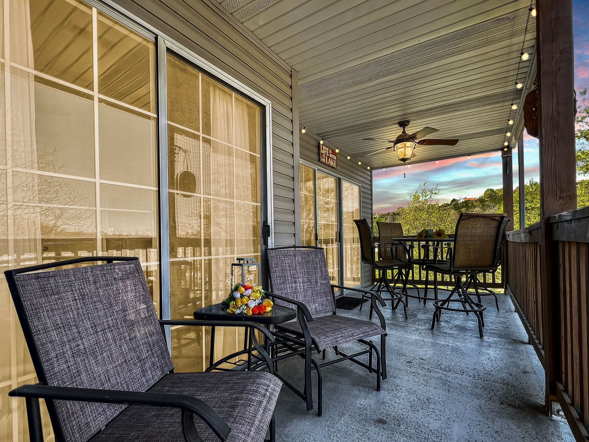 A porch with chairs , a table and a ceiling fan