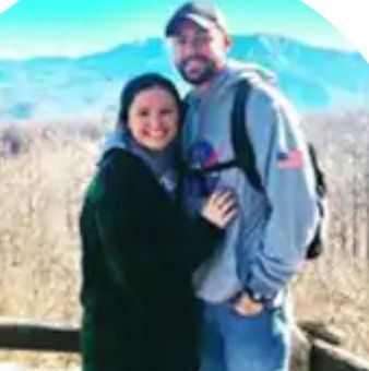 A man and a woman are posing for a picture on top of a mountain.