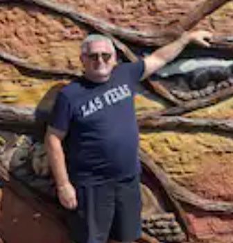 A man in a las vegas shirt is standing in front of a painting.