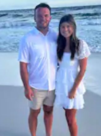 A man and a woman are posing for a picture on the beach.