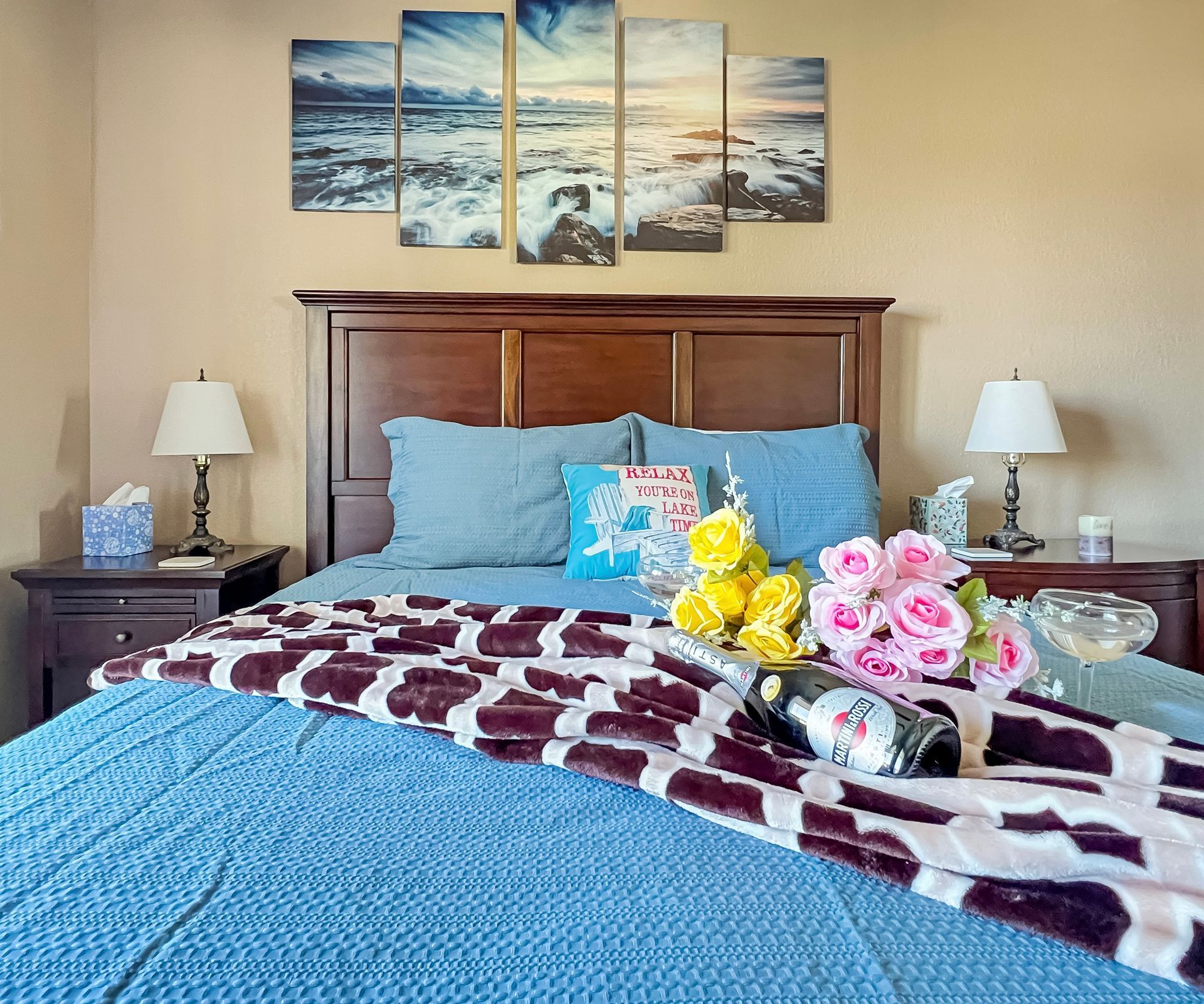 A bedroom with a bed , nightstands , lamps and a bottle of wine on the bed.