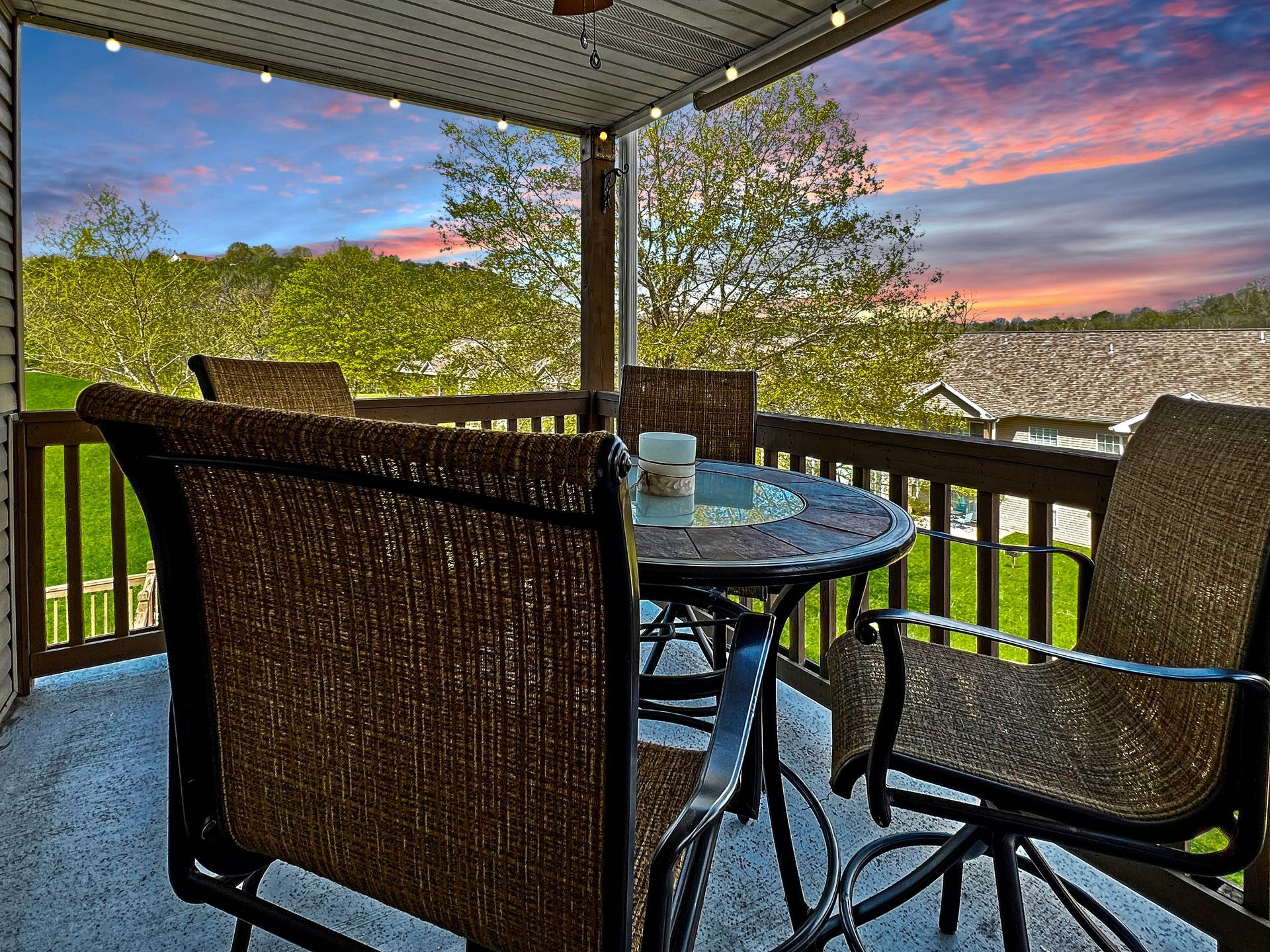A patio with a table and chairs and a sunset in the background.