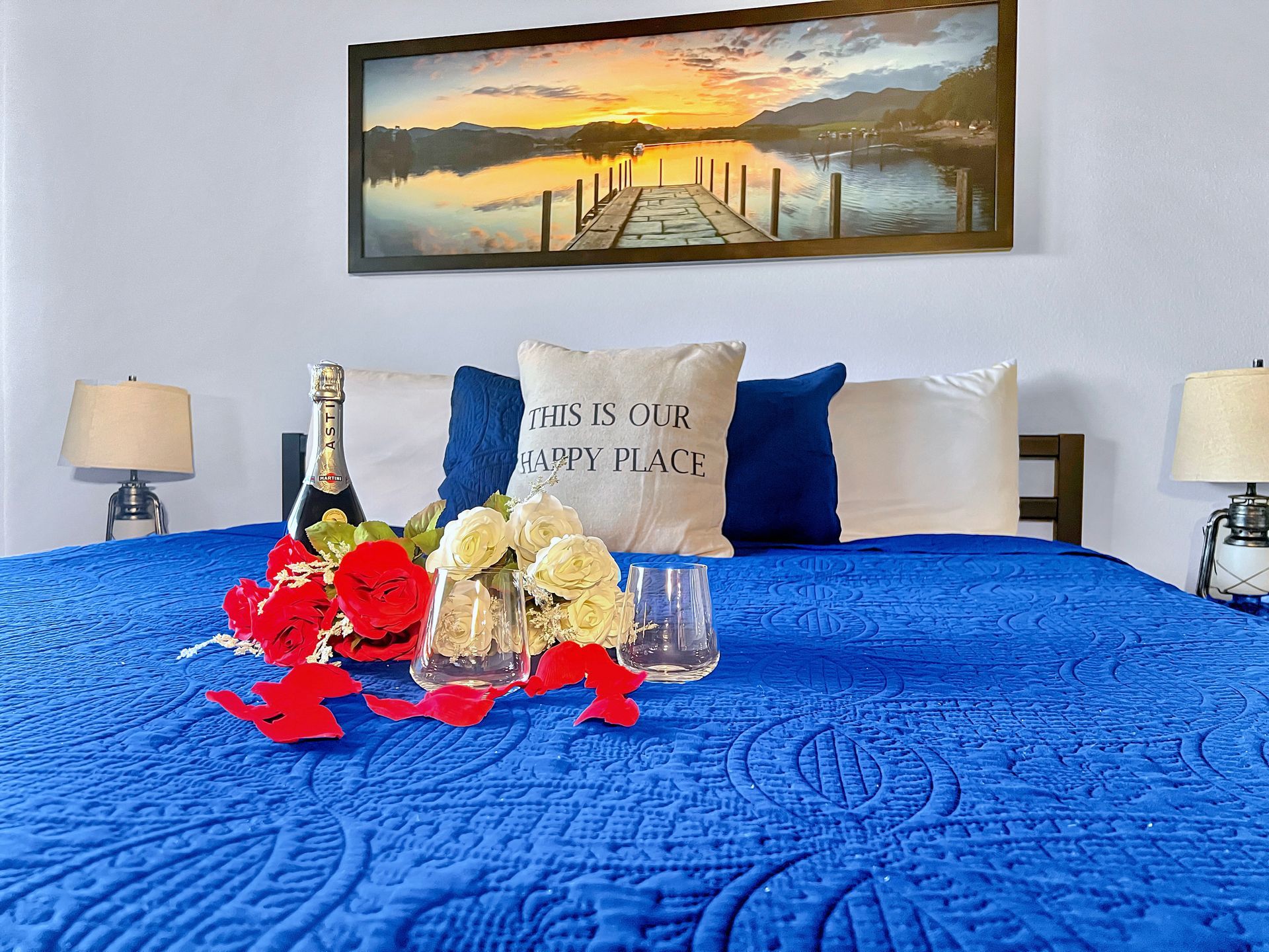 A bed with a blue blanket and a pillow that says `` this is our happy place ''.