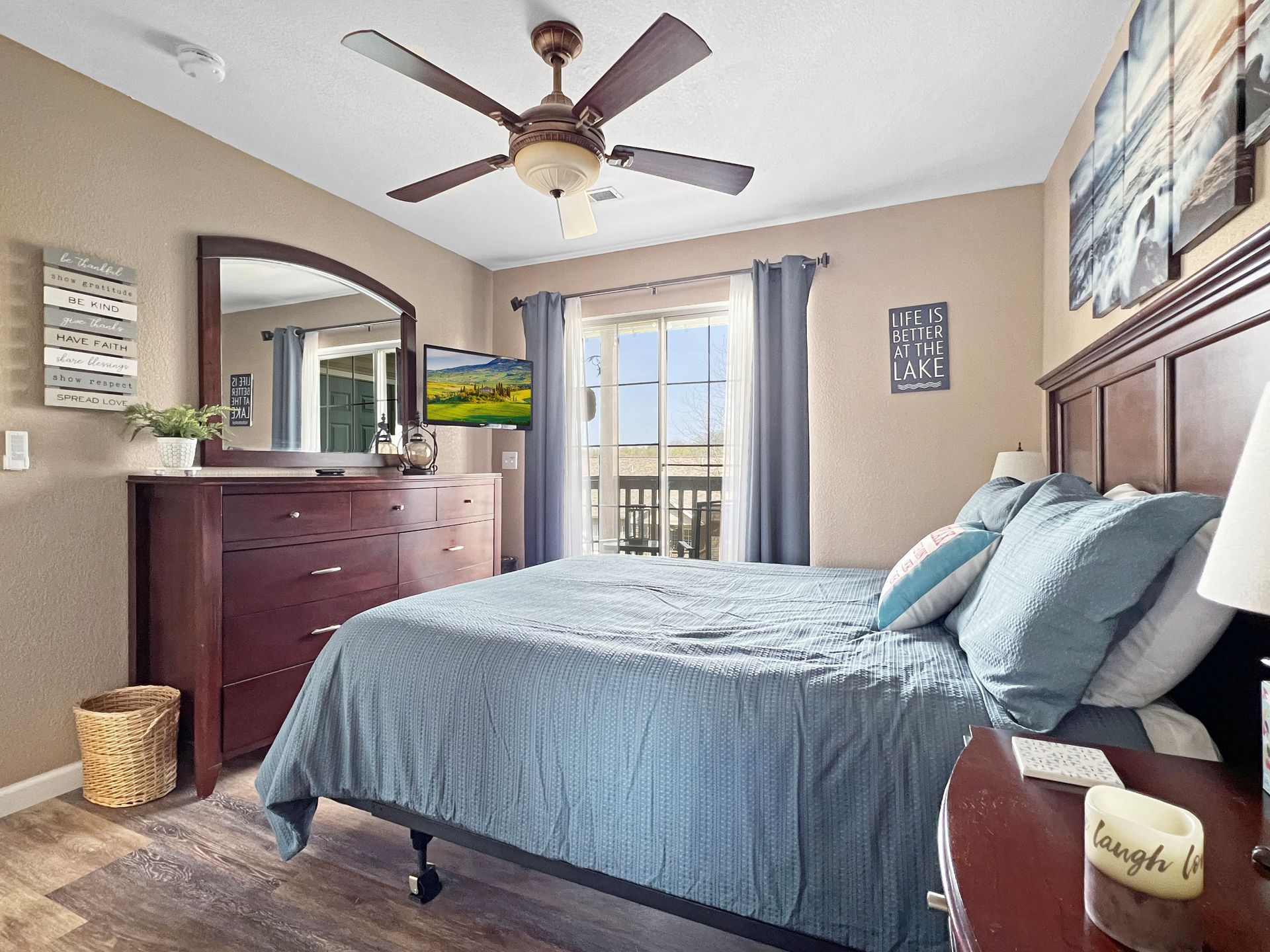 A bedroom with a bed , dresser , mirror and ceiling fan.