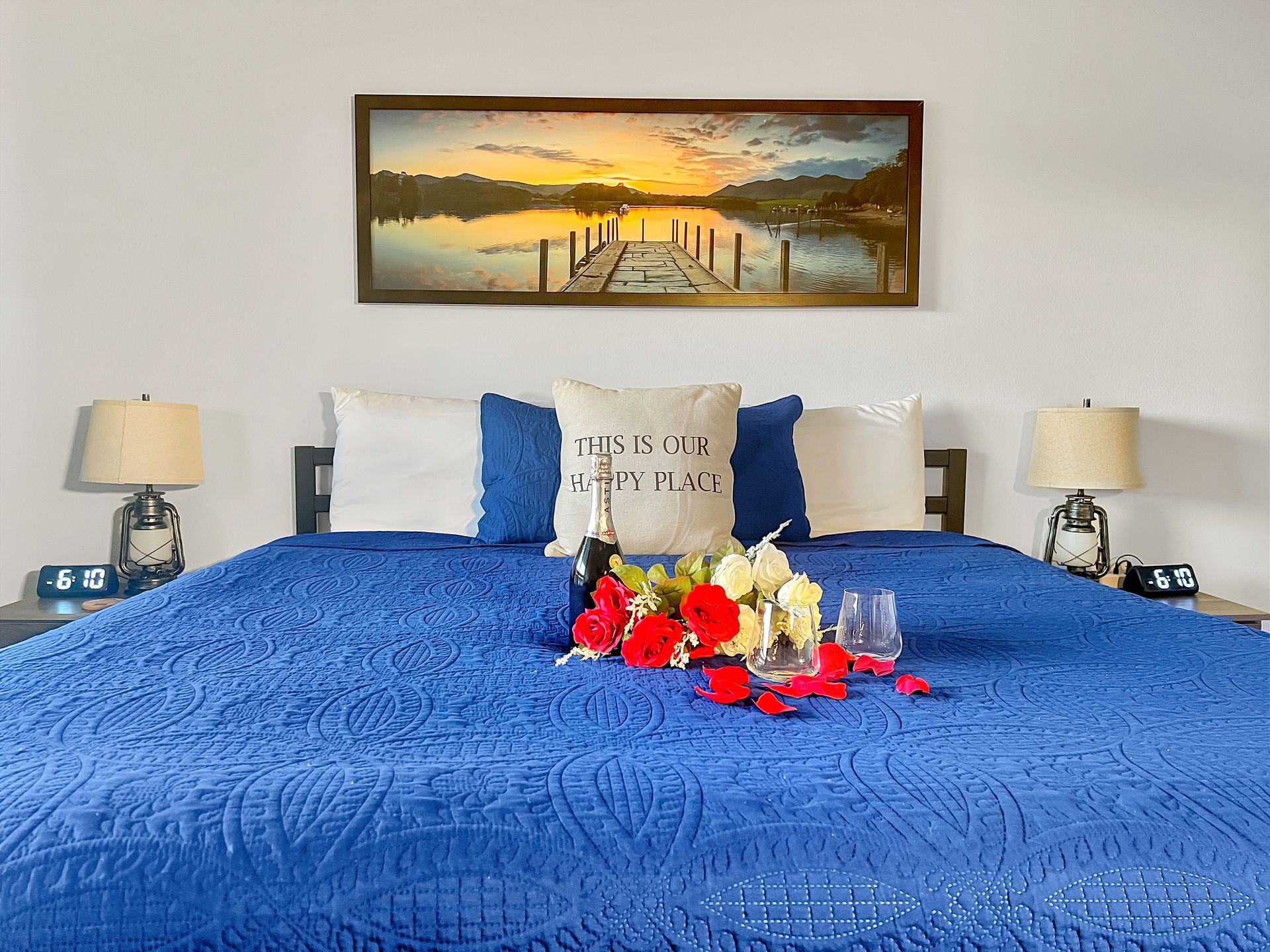A bed with a blue blanket and a picture on the wall above it.
