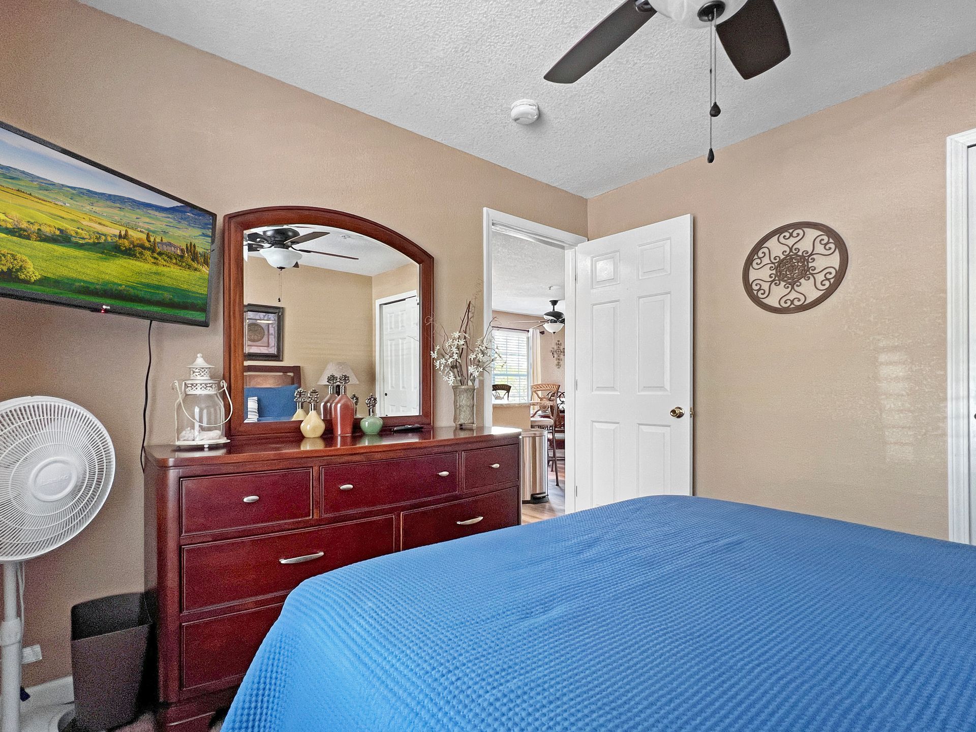 A bedroom with a bed , dresser , mirror and ceiling fan