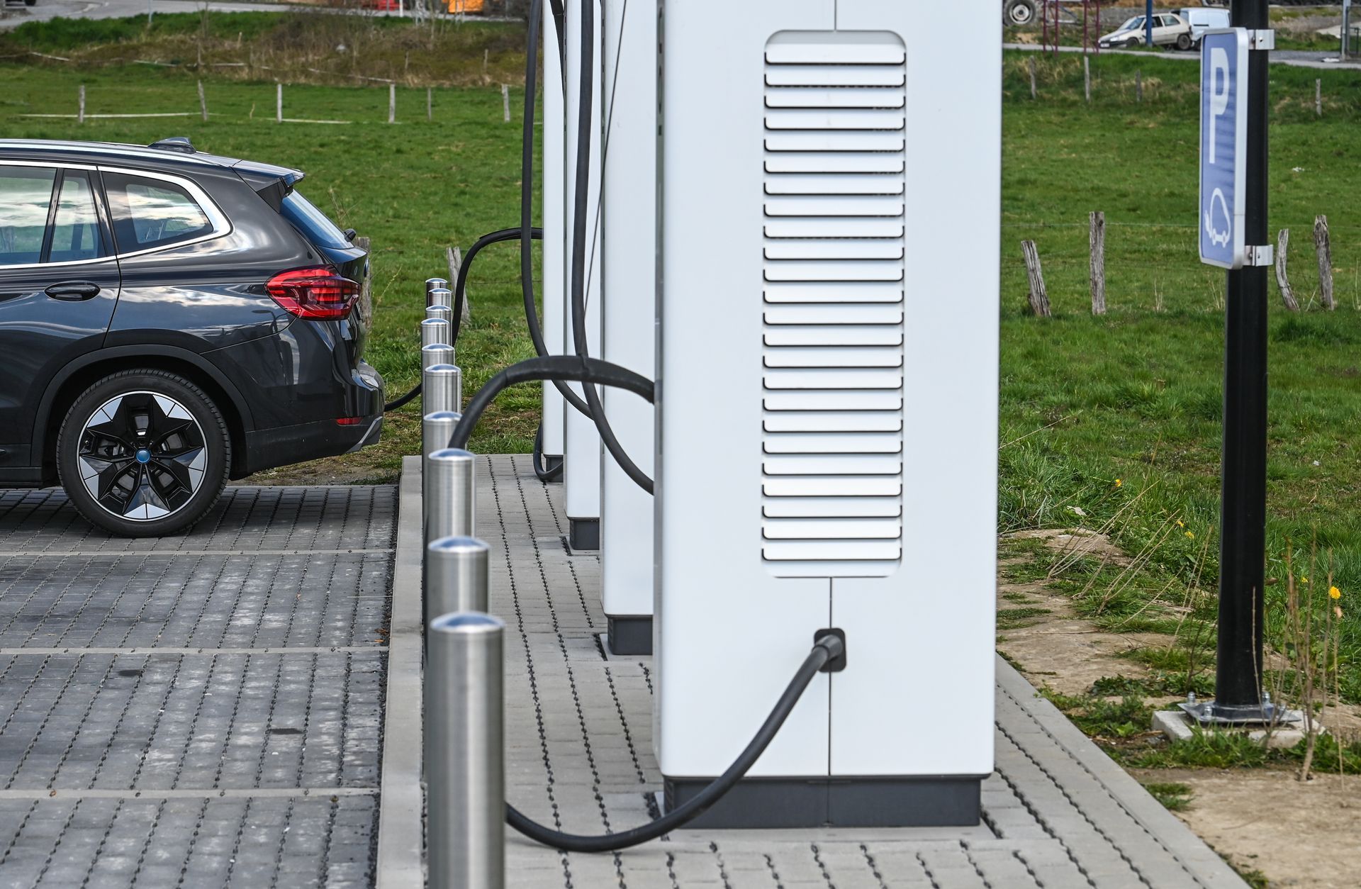 SUV électrique branché à une borne de recharge sur un parking pavé.