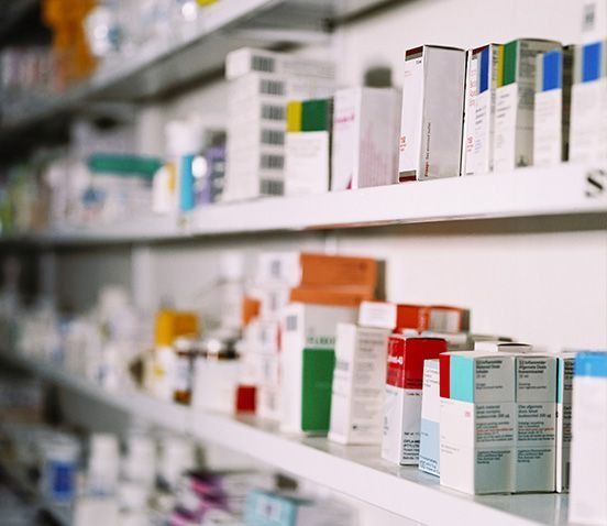 Estantes llenos de diversas cajas y frascos de medicamentos en una farmacia.