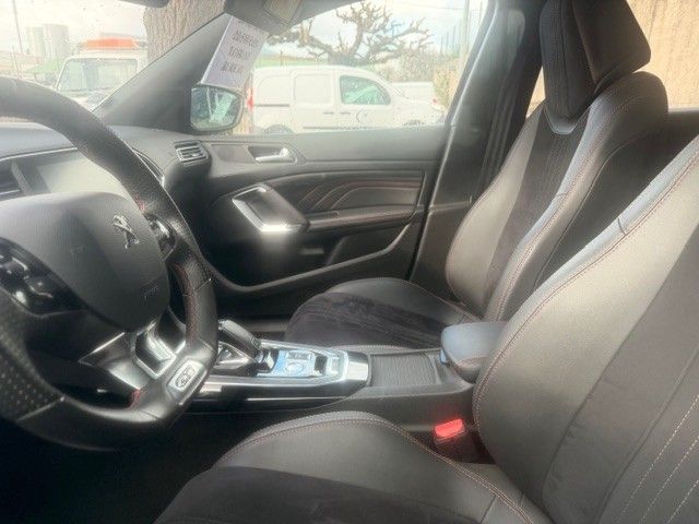 Intérieur d'une voiture. Sièges, volant et console en cuir noir. Une camionnette est visible par la fenêtre.