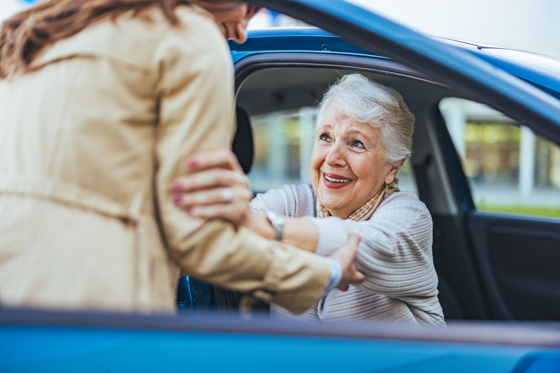 Une femme qui aide une personne âgée à sortir d'une voiture