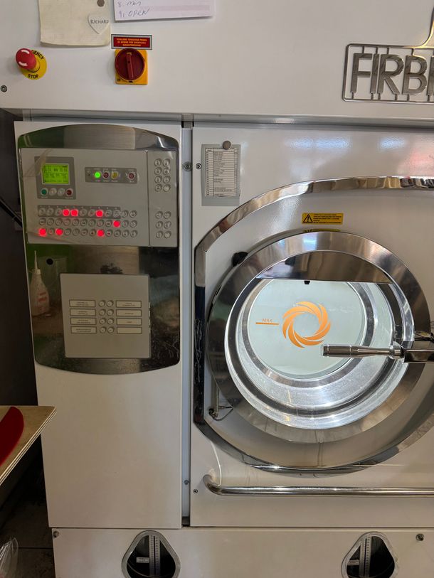 Industrielle Trockenreinigungsmaschine mit offener Tür und Bedienfeld.