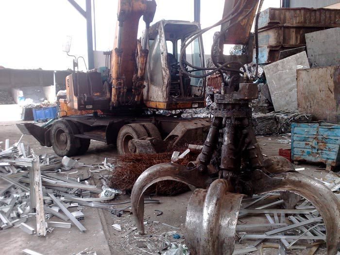 Una gran excavadora está trabajando en una pila de chatarra en un almacén.