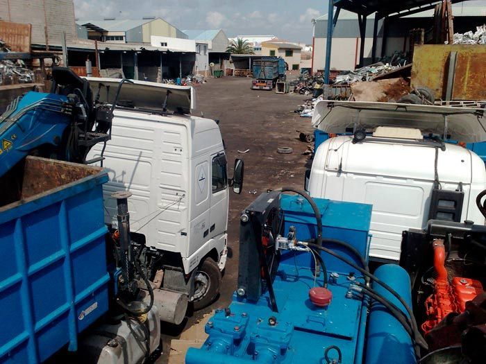 Un camión blanco está estacionado al lado de un camión azul en un estacionamiento.