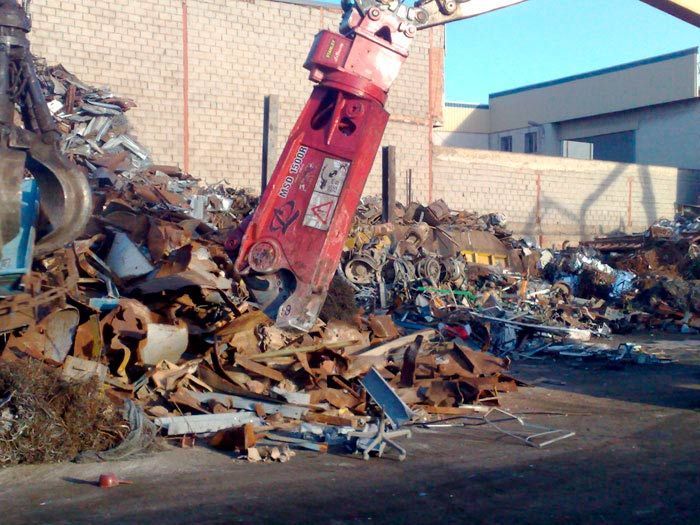 Una gran pila de chatarra con una máquina roja en primer plano.