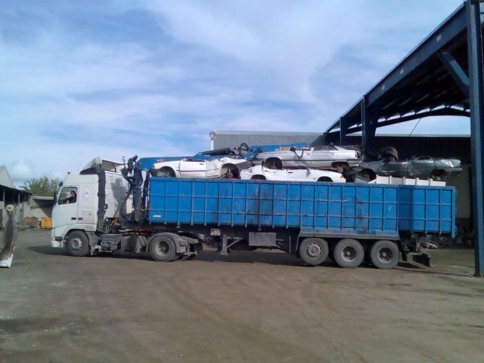 Un camión azul está cargado de coches en un estacionamiento.