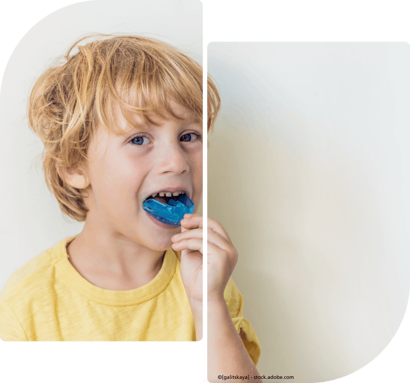 Ein kleiner Junge hält ein blaues Plastikteil vor den Mund, Praxis Dialog - Praxis für Logopädie