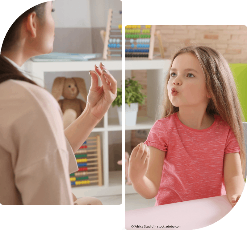 Eine Frau spricht mit einem kleinen Mädchen, das an einem Tisch sitzt. Praxis Dialog - Praxis für Logopädie