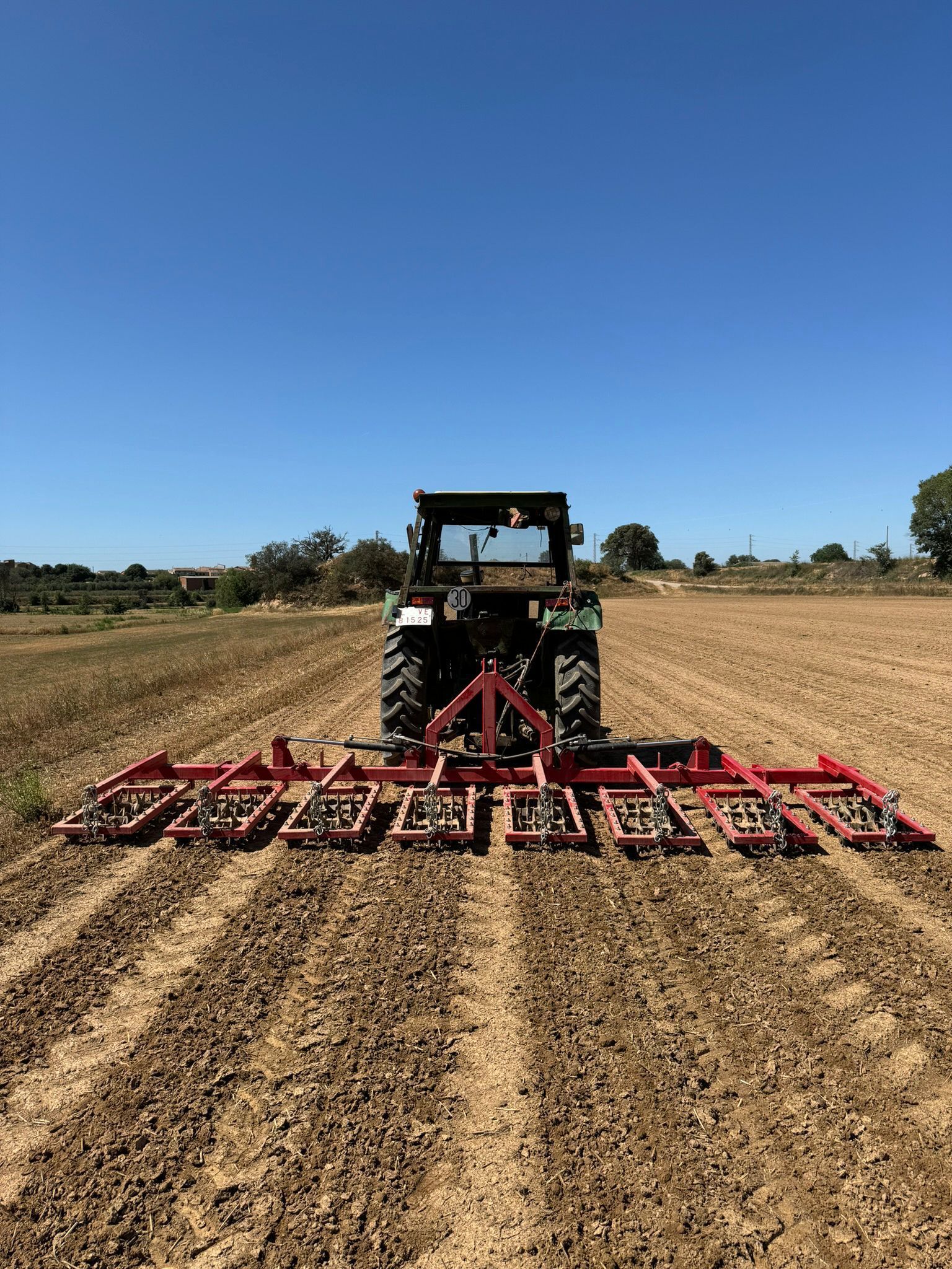 Un tractor está arando un campo con una máquina.