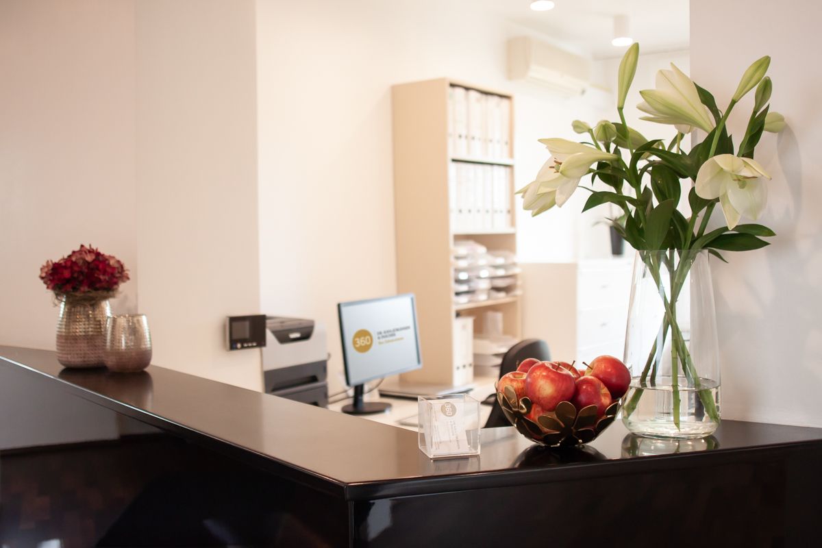 Ein Empfangstresen in einem Büro mit einer Vase mit Blumen darauf.