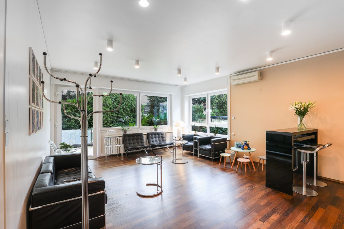 Ein Wartezimmer mit Sofa, Stühlen und Tischen.