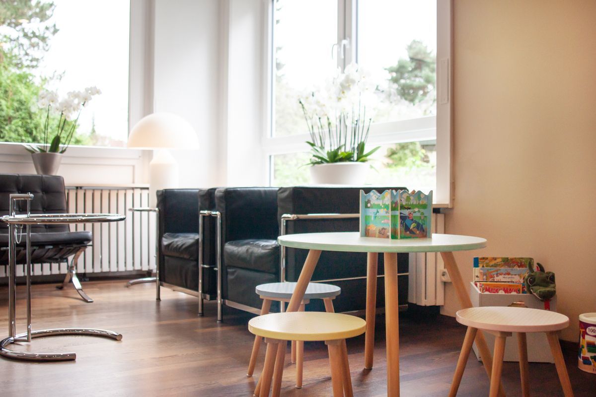 Ein Wartezimmer mit einem Tisch, Stühlen und einem Fenster.