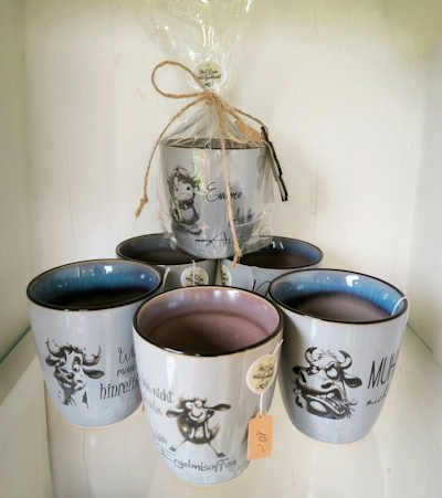 Auf einem Tisch stehen mehrere Tassen mit Kühen darauf übereinander.