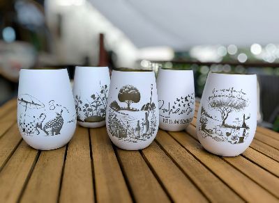 Eine Gruppe gravierte Weingläser steht auf einem Holztisch.