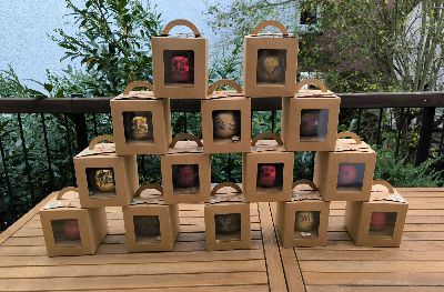 Ein Haufen übereinander gestapelter Kisten mit Christbaumkugeln auf einem Holztisch.