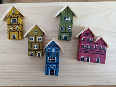 Eine Gruppe von bemalten Holzhäusern steht auf einem Holztisch.