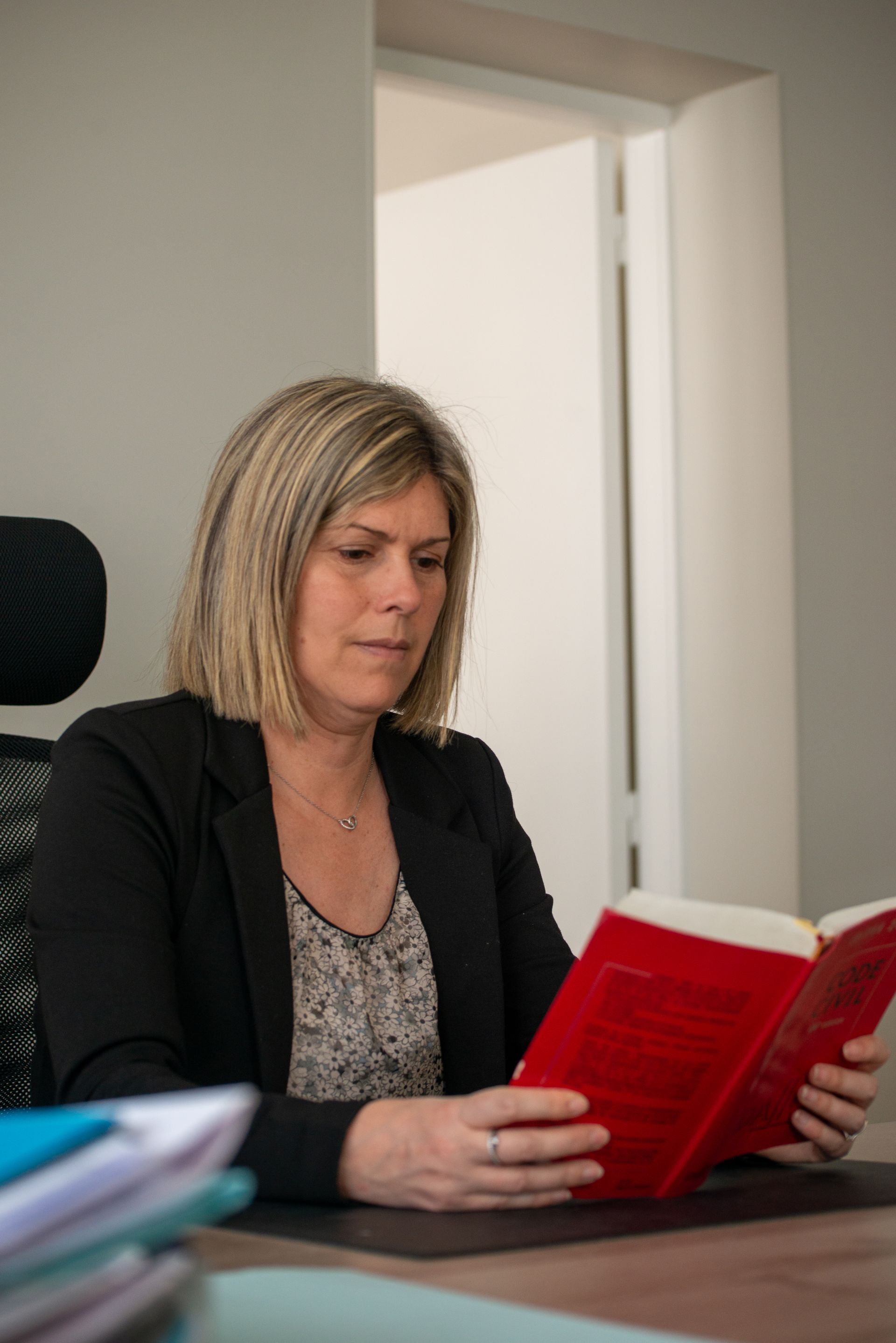 Une personne lisant un livre rouge à un bureau dans un bureau lumineux